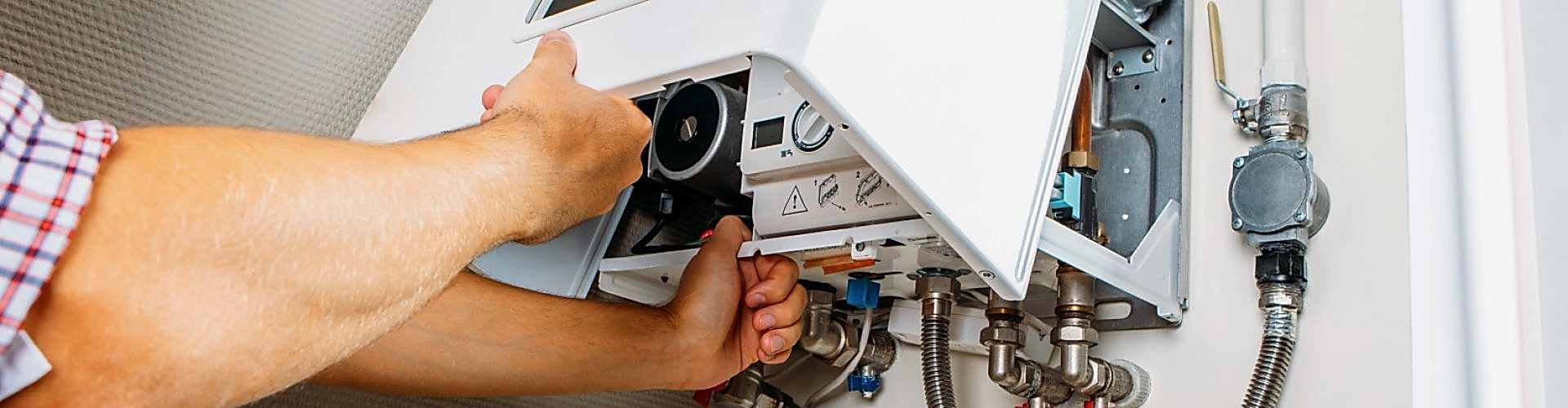 Plumber attaches Trying To Fix the Problem with the Residential Heating Equipment. Repair of a gas boiler